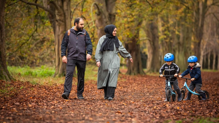 Visitors walking along an avenue at Anglesey Abbey. Children are on balance bikes.